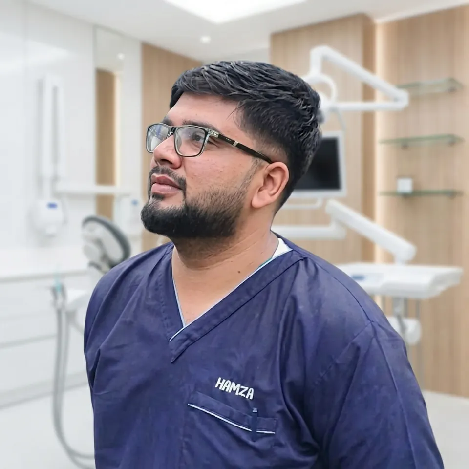 Dr. Ali Hamza in navy scrubs in a dental treatment room