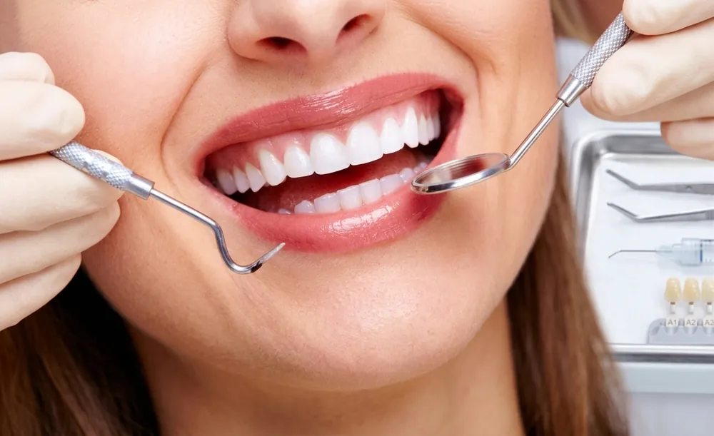 Dental checkup with a mouth mirror and probe on a patient's healthy white smile